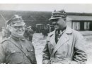 Fotografia: Mikołaj Aksan w mundurze podporucznika (z lewej) z kolegą na tle budynków.