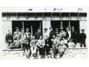 Fotografia grupowa osób w ubraniach cywilnych na tle budynku w trakcie budowy: Edward Bagiński stoi piąty od lewej.